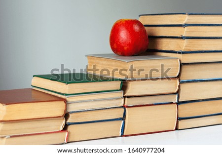 stack of hardback books on white table with red apple. Books stacking. Back to school concept. Copy Space. Education learning background