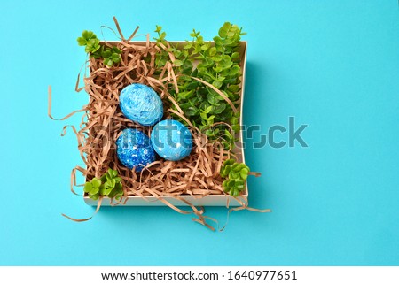 Spring Easter colorful painted eggs in the box on the blue background flat lay closeup top view beautiful picture. Congratulations card happy holiday