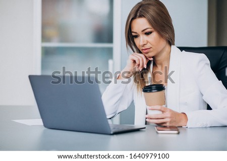 Beautiful business woman working on computer in office and drinking coffee