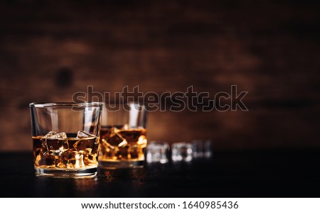 Whisky, bourbon or cognac with ice cubes on black stone table and wood background Royalty-Free Stock Photo #1640985436