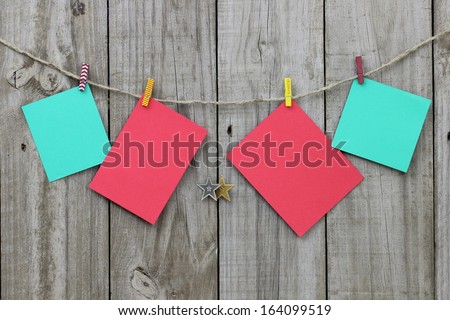 Blank Christmas note cards hanging from clothesline by antique rustic wood background; Christmas background with red and green copy space