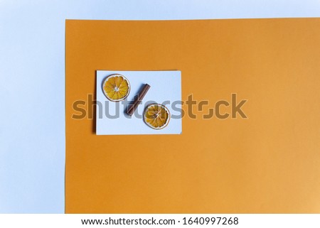 two dry orange slices, cinnamon stick as percent sign on white and yellow background