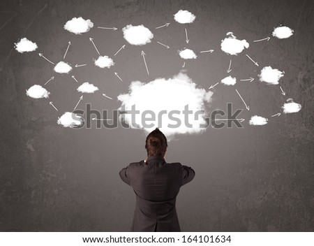 Young businessman sitting in office chair in front of a wall with cloud technology concept above his head