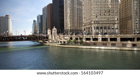 Architecture on a grand scale lines the Chicago River where it flows beneath the DuSable Bridge. Royalty-Free Stock Photo #164103497