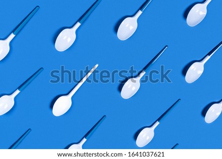 Picture of white plastic spoons on blue background. Flat lay, top view, copy space.