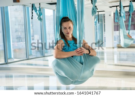 Woman practices aerial yoga in hammock . Anti-gravity relaxing kind of sport. Health, fly yoga concept.