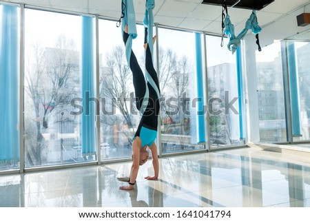 Woman practices aerial yoga in hammock . Anti-gravity relaxing kind of sport. Health, fly yoga concept.