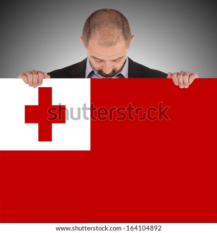 Smiling businessman holding a big card, flag of Tonga