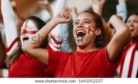 Female soccer fans of England watching and celebrating their team's victory. English female spectators enjoying after a win at stadium. Royalty-Free Stock Photo #1641052237