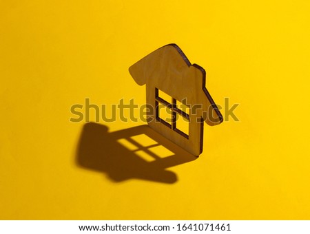 Mini house figure on a yellow background. Studio shot with shadow