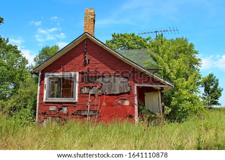 A small wooden abandoned house with red fake brick siding. Royalty-Free Stock Photo #1641110878