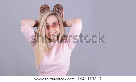 Portrait of caucasian woman with chocolate donuts posing on gray background.