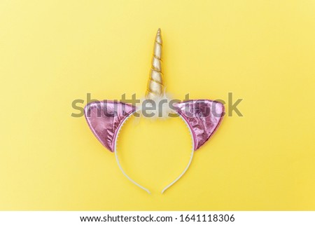 Kawaii unicorn concept. Simply flat lay design Halloween party accessory unicorn horn hairband isolated on yellow colorful background. Fantasy rainbow horse symbol