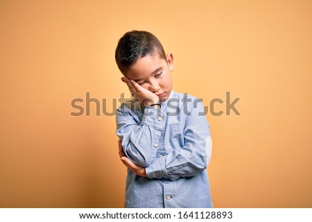 Young little boy kid wearing elegant shirt standing over yellow isolated background thinking looking tired and bored with depression problems with crossed arms.