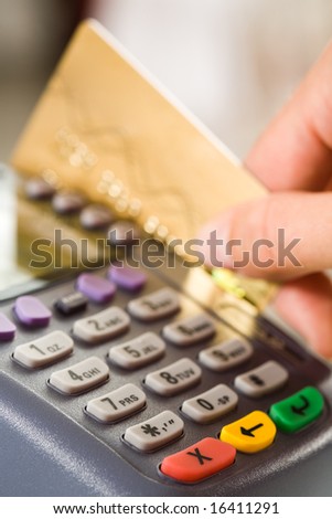 Close-up of payment machine buttons with human hand holding plastic card near by