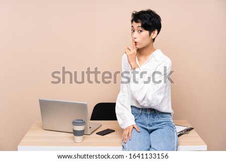 Young business Asian girl in her workplace doing silence gesture