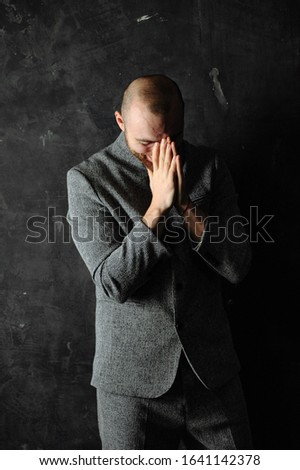 Picture of a young guy having put hands together in prayer or meditation, dreaming and waiting for all best