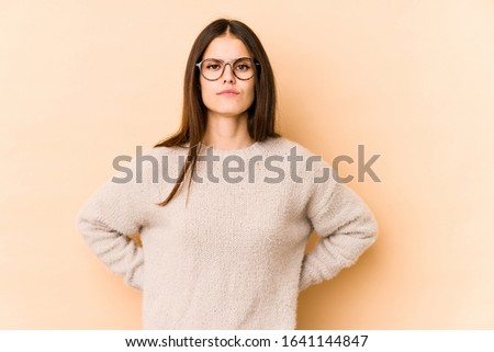 Young caucasian woman isolated on beige background sad, serious face, feeling miserable and displeased.