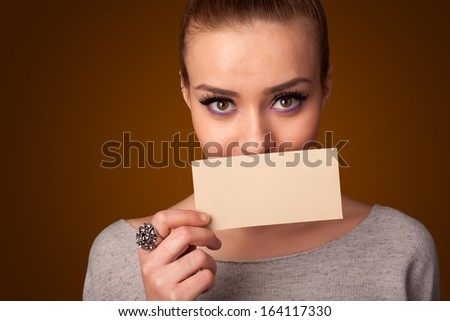 Cute girl holding white card at front of her lips with copy space on gradient background