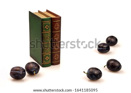 Books and ripe purple plums on a white background. Still life with fruit and box-stash.