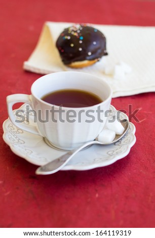 A cup of tea with fresh chocolate sufgniya (donut)