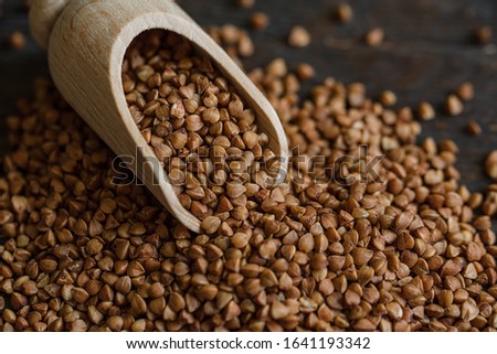 Scoop and buckwheat macro view on rustic background. Close up raw buckwheat background. gluten free ancient grain for healthy diet, selective focus Royalty-Free Stock Photo #1641193342