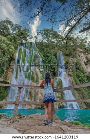 Travel and freedom. Young woman enjoying tropical waterfall view.