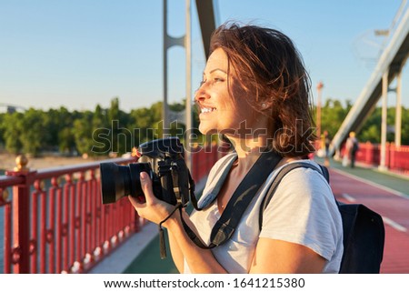 Mature woman photographer with camera taking photo picture. Female blogger, freelancer working with smile and enjoyment
