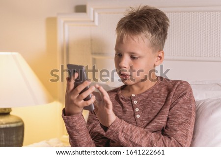 Little kid texting messages at social media application using mobile smartphone.