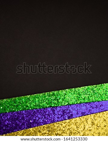 Shiny green, purple and golden stripes geometric border frame on black paper background with empty space for copy, room for text. Vertical Mardi Gras holiday poster backdrop.