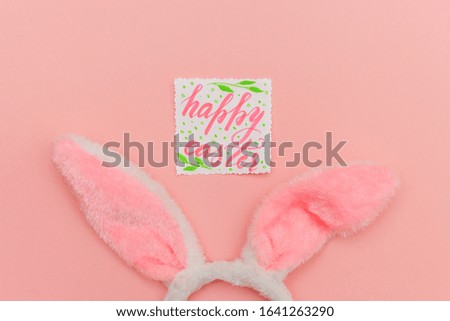 Happy Easter concept. Preparation for holiday. Inscription HAPPY EASTER letters decorative bunny ears isolated on trendy pastel pink background. Simple minimalism flat lay top view copy space