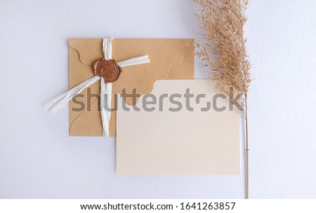 Craft envelope with business card mock up decorated wtih pampas grass on white background