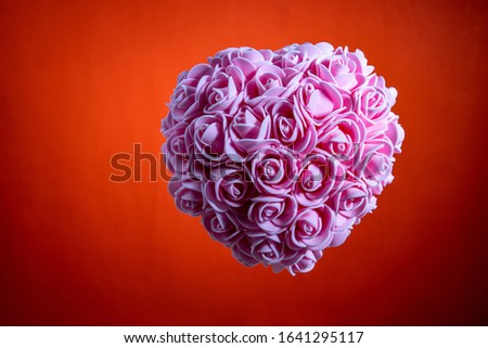 Valentine's Day, romantic still life, pink heart of pink flowers, blurred red background, shallow depth of field. Beautiful holiday picture.