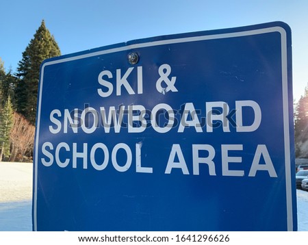 Ski and Snowboard School Area signboard at a winter ski resort.