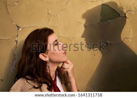 Beautiful througtful young woman thinks of her ideal boyfriend man or lover represented by a shadow on the wall. Royalty-Free Stock Photo #1641311758