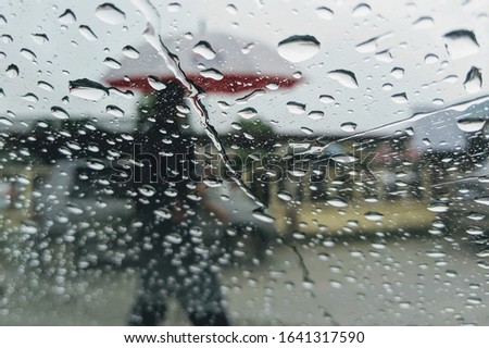 Street in the heavy rain. Water drops or rain in front of mirror of car on road or street. Driving in rain. Blurred background.