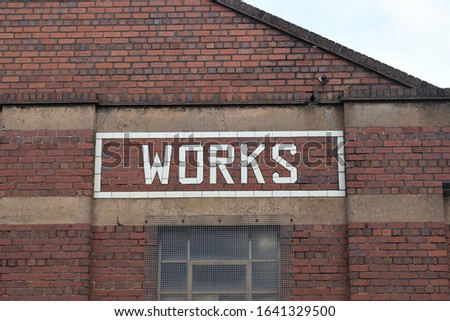 Works Sign in Glazed White Brick on Wall of Old Factory Building 