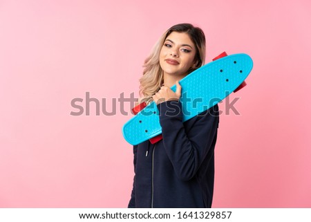 Teenager girl over isolated pink background with skate