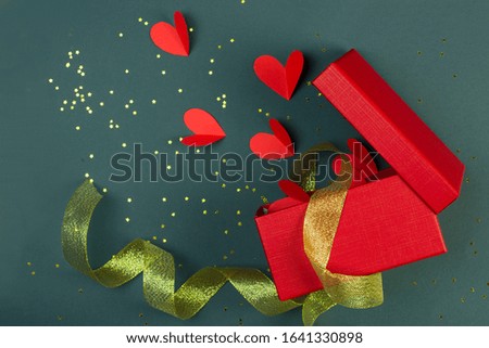 Holiday gift in a red box and with a gold ribbon many hearts, the concept of the holiday, love and Valentine's Day,place for text