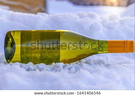 wine bottle on stones in the snow in the middle of winter at the beginning of a sunny day 