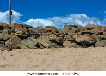 View of  the  sandy beach near the rocks on a  rocky groyne  by the land backed harbour in Bunbury South Western Australia on a sunny spring morning.