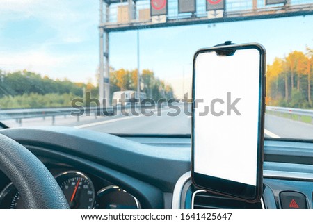 The smartphone in the car is used for navigation or GPS. The movement of the car with a smartphone in the holder. Mobile phone isolated white screen. Copy spaces. Vehicle interior. Mock-up.