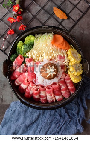 Beef rolls and vegetable ingredients in a black hot pot