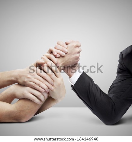arm wrestling: businessman in opposition with many hands on gray background