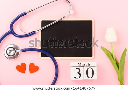 Doctor's Day concept, flat lay top view, equipment medical red heart stethoscope on pink background, care patient in hospital with black board copy space for text