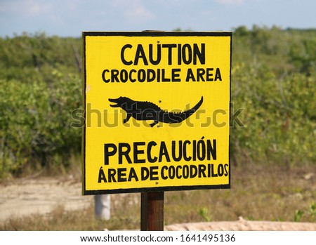 A bilingual sign in English and Spanish that says "Caution Crocodile Area" at Punta Sur Eco Park in Cozumel, Mexico