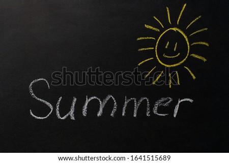 the inscription "summer" written in white chalk on a black chalkboard. The sun drawn on a blackboard.