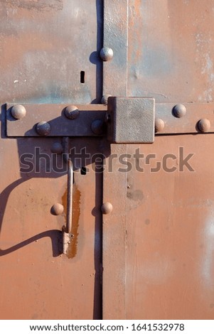 An old, rusty padlock on an iron gate.