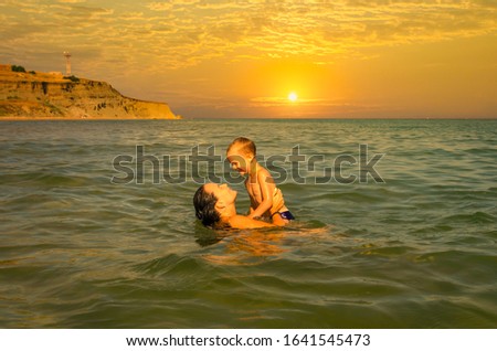 A mother with a young son swims in the sea in the summer.