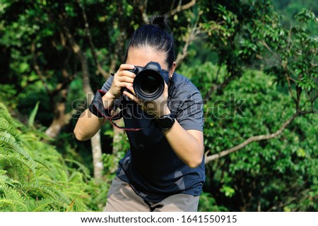 Photographer taking photo in the forest with digital camera